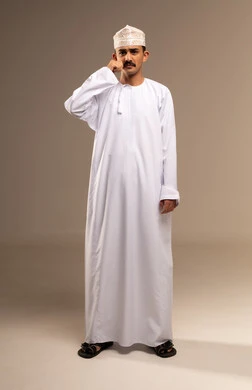 اليوم العالمي للرجل 19 نوفمبر، مناسبات عالمية سنوية، بورتريه لرجل عربي خليجي عماني يرتدي الدشداشة والكمه ويمسك بيده شاربه الاسود، الوقوف باستقامة والنظر إلى الكاميرا والإشارة إلى الشنب، مفهوم الاهتمام بالرجل،  مفهوم القوة والرجولة، خلفية بيج