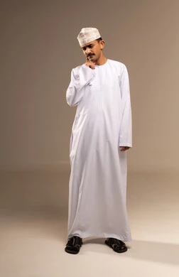 طلب العلاج والمساعده، إلتهاب اللثه و تسوس الأضراس، يعاني من مشاكل صحية في الاسنان ، بورتريه لرجل عربي خليجي عماني يرتدي الدشداشة والكمه يضع يده على خده بإيماءات تدل على الشعور بألم الأسنان، الحاجه لزيارة الطبيب، الجسم بالطول الكامل, خلفية بيج