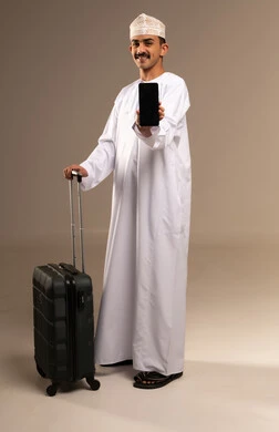 A black phone screen background, looking at something with expressions of excitement and joy, spending enjoyable times on vacation, the concept of tourism and travel, a portrait of a young Arab Gulf Omani man wearing a dishdasha and a kumma holding a travel bag in his hand, preparing for travel time, full body, beige background.