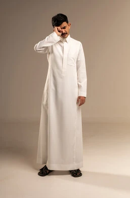 الإحساس بالكسل والخمول و الإرهاق،الشعور بالتعب والحاجة الى النوم والراحة,  بورتريه لشاب عربي خليجي سعودي  يرتدي الزي التقليدي  يضع يده على فمه بإيماءات التثاؤب والنعاس، صورة الجسم بالطول الكامل, خلفية رمادية