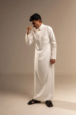 الشعور بالتعب والحاجة الى النوم والراحة, الإحساس بالكسل والخمول و الإرهاق، بورتريه لشاب عربي خليجي سعودي  يرتدي الزي التقليدي  يضع يده على فمه بإيماءات التثاؤب والنعاس، صورة الجسم بالطول الكامل, خلفية رمادية