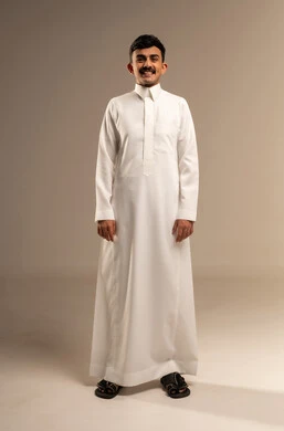 العناية والتجميل والتبيض، تعابير السرور باستخدام قشور فينير من الخزف، بورتريه لشاب عربي خليجي سعودي مبتسم يرتدي الزي التقليدي ينظر إلى الكاميرا يشير بيديه إلى أسنانه, أهمية متابعة طبيب الاسنان، خلفية رمادية