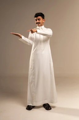 الاناقة والاهتمام بالمظهر, الإشارة إلى شيء ما، بورتريه لشاب عربي خليجي سعودي يرتدي الزي الرسمي ينظر إلى يده و يشير بإصبع السبابة إليها, الجسم بالطول الكامل، خلفية رمادية