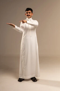 الاناقة والاهتمام بالمظهر, الإشارة إلى شيء ما، بورتريه لشاب عربي خليجي سعودي يرتدي الزي الرسمي ينظر إلى يده و يشير بإصبع السبابة إليها, الجسم بالطول الكامل، خلفية رمادية
