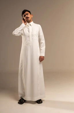 التركيز على الكلام و محاولة سماع الأصوات، الانصات وحسن الاستماع, حدوث ضعف في السمع, بورتريه لرجل عربي خليجي سعودي يرتدي الثوب التقليدي يضع يده خلف اذنه بإيماءات التنصت, الجسم بالطول الكامل, خلفية رمادية