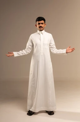 Expressions of confusion, bewilderment, and questioning, inquiry and curiosity about a specific thing, a portrait of a young Arab Gulf Saudi teenager wearing formal attire, gesturing with his hands in expressions of surprise and astonishment, with a gray background.