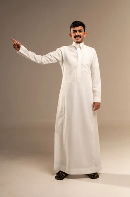 Indicating and clarifying something, specifying a certain location, pointing to the place of an element, a portrait of a young Arab Gulf Saudi man wearing traditional attire pointing with his index finger to something, full-body image, gray background.