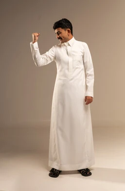 زيادة قدرة العضلات على التحمل، إتقان فنون الملاكمة، بورتريه لشاب عربي خليجي سعودي يرتدي الثوب التقليدي يرفع قبضة يديه بإيماءات القوة، ايماءات  و تعابير الثقة بالنفس، ممارسة رياضة الدفاع عن النفس، الجسم بالطول الكامل، خلفية رمادية