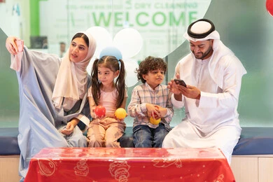 قضاء الاوقات السعيده مع الابناء ، مركز ألعاب ترفيهي،استخدام الجوال لتوثيق اللحظات التذكاريه ، أجواء تفاعلية مبهجة ، تعابير السرور والسعادة، سيده اماراتيه تلتقط صور السيلفي ،مشاركة الأب والأم أطفالهما لحظات المرح والحماس ،عائلة عربية خليجية إماراتية تستمتع بوقت ممتع في لعبة الرمي التفاعلية