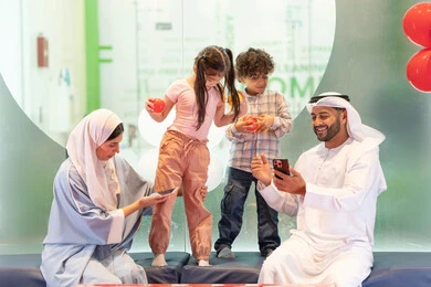 استخدام الجوال لتوثيق اللحظات التذكاريه ، التقاط صور السيلفي ، مركز ألعاب ترفيهي، مشاركة الأب والأم أطفالهما لحظات المرح والحماس ،  أجواء تفاعلية مبهجة ، عائلة عربية خليجية إماراتية تستمتع بوقت ممتع في لعبة الرمي التفاعلية ،تعابير السرور والسعادة،  قضاء الاوقات السعيده مع الابناء