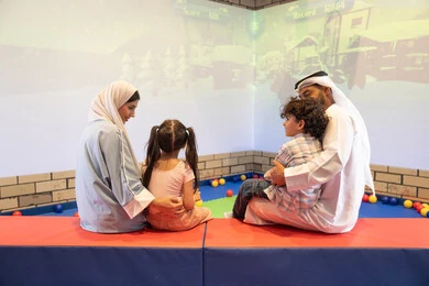 صوره من الخلف لعائلة عربية خليجية إماراتية تستمتع بوقت ممتع في لعبة الرمي التفاعلية ، أجواء تفاعلية مبهجة ،قضاء الاوقات السعيده مع الابناء ، مركز ألعاب ترفيهي، مشاركة الأب والأم أطفالهما لحظات المرح والحماس ، تعابير السرور والسعادة