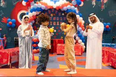 المراكز الترفيهيه المسلية في الامارات العربية،استخدام الجوال فى توثيق اللحظات التذكاريه ، مفهوم التسلية والترفيه، دمج التقنيات المتطوره فى الحياه اليوميه، مشاعر المتعة والفرح، قضاء أوقات سعيده في أرض المرح، عائله عربيه خليجيه اماراتيه تستمتع باللعب فى مدينة الملاهي ، تلعب بالكور الملونه