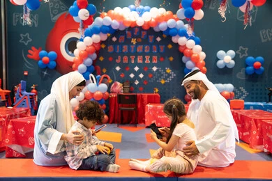 المراكز الترفيهيه المسلية في الامارات العربية، قضاء أوقات سعيده في أرض المرح،عائله عربيه خليجيه اماراتيه تستمتع باللعب فى مدينة الملاهي وتستخدم الجوال ، مشاعر المتعة والفرح، مفهوم التسلية والترفيه، دمج التقنيات المتطوره فى الحياه اليوميه