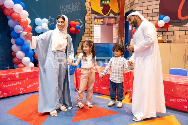 مشاعر المتعة والفرح، المراكز الترفيهيه المسلية في الامارات العربية،قضاء أوقات سعيده في أرض المرح، عائله عربيه خليجيه اماراتيه تستمتع باللعب فى مدينة الملاهي، ام اماراتيه تشير الى مكان ما ،مفهوم التسلية والترفيه، الانشطة الترفيهية الممتعه