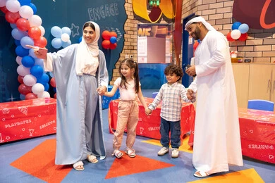 Feelings of fun and joy, entertaining entertainment centers in the UAE, spending happy times in the land of fun, an Arab Gulf Emirati family enjoying playing in an amusement park, an Emirati mother pointing to a place, the concept of entertainment and fun, enjoyable recreational activities