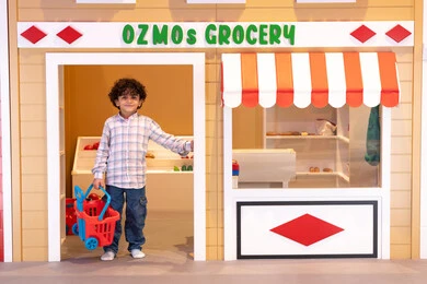 ولد عربي خليجي اماراتي يرتدي الزى الكاجوال، يجر عربه التسوق،النظر الى الكاميرا بايماءات السعاده، اللعب في قسم البقالة، قضاء وقت ممتع في مركز الالعاب الترفيهيه،  تعلم تسوق الخضار الطازجة ، دعم وتنمية مهارات الأطفال، طعام صحي ومفيد