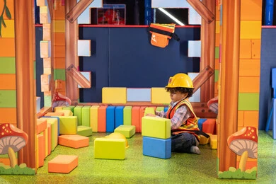 تعزيز المهارات الذهنية والفكرية، قضاء أوقات ممتعة باللعب والتركيز، ولد عربي خليجي إماراتي يرتدي الخوذة وسترة الحماية يقوم بتركيب المكعبات ، مراكز الالعاب الترفيهيه في الامارات، رعاية وتطوير مهارات الأطفال