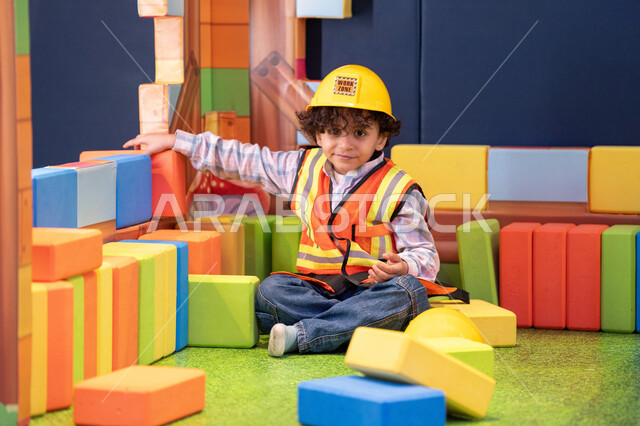 الابداع وتنمية المهارات الذهنية والفكرية،ولد عربي خليجي إماراتي يرتدي الخوذة وسترة الحماية يقوم بتركيب المكعبات ،  مراكز الالعاب الترفيهيه في الامارات، قضاء أوقات ممتعة باللعب والتركيز، رعاية وتطوير مهارات الأطفال