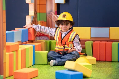 الابداع وتنمية المهارات الذهنية والفكرية،ولد عربي خليجي إماراتي يرتدي الخوذة وسترة الحماية يقوم بتركيب المكعبات ،  مراكز الالعاب الترفيهيه في الامارات، قضاء أوقات ممتعة باللعب والتركيز، رعاية وتطوير مهارات الأطفال