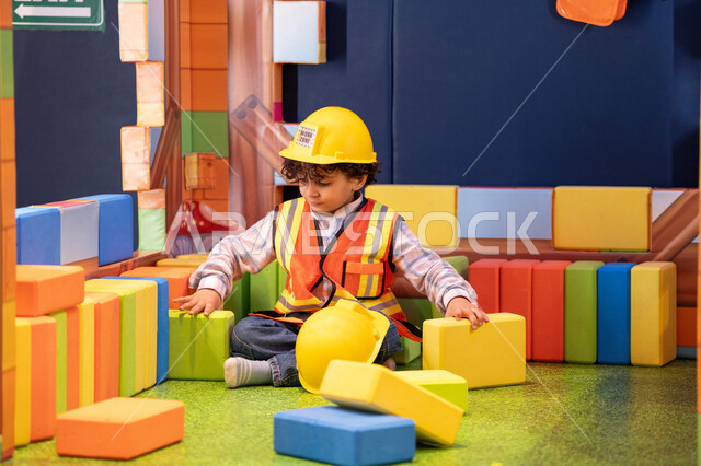 تعزيز المهارات الذهنية والفكرية، مراكز الالعاب الترفيهيه في الامارات، قضاء أوقات ممتعة باللعب والتركيز،  رعاية وتطوير مهارات الأطفال،ولد عربي خليجي إماراتي يرتدي الخوذة وسترة الحماية يقوم بتركيب المكعبات