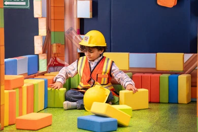 تعزيز المهارات الذهنية والفكرية، مراكز الالعاب الترفيهيه في الامارات، قضاء أوقات ممتعة باللعب والتركيز،  رعاية وتطوير مهارات الأطفال،ولد عربي خليجي إماراتي يرتدي الخوذة وسترة الحماية يقوم بتركيب المكعبات