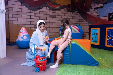 تعلم تسوق المنتجات الطازجة من خلال سلة مليئة بالخضار والفواكه البلاستيكية، تعزيز مفهوم الغذاء الصحي والمتوازن،دعم وتنمية مهارات الأطفال،  أجواء مليئة بالمرح والسرور،  سيدة عربية خليجية إماراتية ترتدي العباءة والحجاب تشارك ابنتها لحظات ممتعه في مركز الألعاب الترفيهية،  قضاء وقت عائلي ممتع مليء بالحب