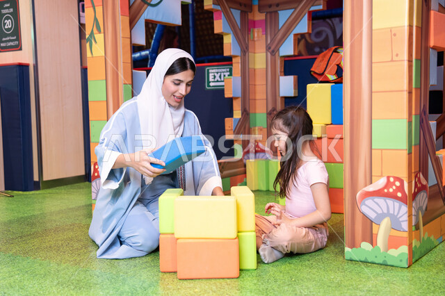 قضاء أوقات ممتعة باللعب والتركيز، الاهتمام ودعم الأبناء،رعاية وتطوير مهارات الأطفال، تعزيز المهارات الذهنية والفكرية،مراكز الالعاب الترفيهيه في الامارات، فتاة عربية خليجية إماراتية ترتدي الخوذة وسترة الحماية، ام عربية خليجية سعوديه تقوم بتركيب المكعبات مع ابنتها