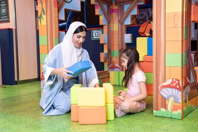 قضاء أوقات ممتعة باللعب والتركيز، الاهتمام ودعم الأبناء،رعاية وتطوير مهارات الأطفال، تعزيز المهارات الذهنية والفكرية،مراكز الالعاب الترفيهيه في الامارات، فتاة عربية خليجية إماراتية ترتدي الخوذة وسترة الحماية، ام عربية خليجية سعوديه تقوم بتركيب المكعبات مع ابنتها