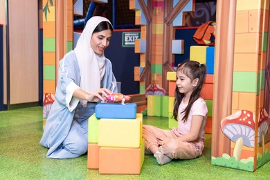 تعزيز المهارات الذهنية والفكرية، الاهتمام ودعم الأبناء، قضاء أوقات ممتعة باللعب والتركيز،  رعاية وتطوير مهارات الأطفال، مراكز الالعاب الترفيهيه في الامارات، فتاة عربية خليجية إماراتية ترتدي الخوذة وسترة الحماية، ام عربية خليجية سعوديه تقوم بتركيب المكعبات مع ابنتها