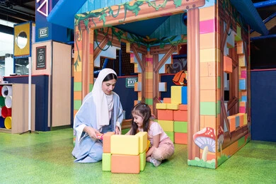 الاهتمام ودعم الأبناء، قضاء أوقات ممتعة باللعب والتركيز،  رعاية وتطوير مهارات الأطفال، مراكز الالعاب الترفيهيه في الامارات، تعزيز المهارات الذهنية والفكرية، فتاة عربية خليجية إماراتية ترتدي الخوذة وسترة الحماية، ام عربية خليجية سعوديه تقوم بتركيب المكعبات مع ابنتها