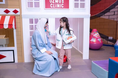 Introducing children to future careers, medicine and healthcare, having fun at the amusement park, the concept of learning through play, an Emirati mother wearing an abaya playing with her daughter, a Saudi Arabian Gulf girl wearing a medical uniform treating her mother