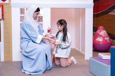 الاهتمام ودعم الابناء، قضاء اوقات مرحه في مركز الالعاب الترفيهي، الطب والرعاية الصحية،  تعريف الأطفال على المهن المستقبلية، أم إماراتية ترتدي عباءة تقوم باللعب مع ابنتها،  فتاة عربية خليجية سعودية ترتدي الزي الطبي تقوم بمعالجه والدتها ،وسائل ايضاح تعليميه ممتعه ، مفهوم التعليم عن طريق اللعب