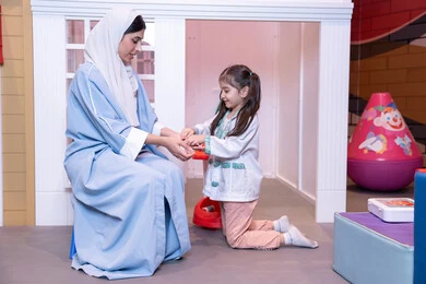 قضاء اوقات مرحه في مركز الالعاب الترفيهي، الطب والرعاية الصحية،  تعريف الأطفال على المهن المستقبلية، أم إماراتية ترتدي عباءة تقوم باللعب مع ابنتها،  فتاة عربية خليجية سعودية ترتدي الزي الطبي تقوم بمعالجه والدتها ،وسائل ايضاح تعليميه ممتعه ، مفهوم التعليم عن طريق اللعب