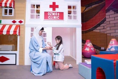 مفهوم التعليم عن طريق اللعب،الاستمتاع في مركز الالعاب الترفيهي، الطب والرعاية الصحية،  تعريف الأطفال على المهن المستقبلية، أم إماراتية ترتدي عباءة تقوم باللعب مع ابنتها، فتاة عربية خليجية سعودية ترتدي الزي الطبي تقوم بمعالجه والدتها
