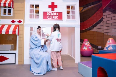 تعريف الأطفال على المهن المستقبلية،  الطب والرعاية الصحية، الاستمتاع في مركز الالعاب الترفيهي، مفهوم التعليم عن طريق اللعب،أم إماراتية ترتدي عباءة تقوم باللعب مع ابنتها، فتاة عربية خليجية سعودية ترتدي الزي الطبي تقوم بمعالجه والدتها