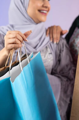 صديقتان سعوديتان تقومان بالتسوق وشراء المستلزمات, بورتريه مقرب لسيدتان عربيتان خليجيتان اماراتيان ترتديان الحجاب والعباءة تحملان بايديهم أكياس كرتون ملونه،الأثر الايجابي للتسوق على نفسية المرأة، ارتداء النظارات الشمسيه للحمايه من اشعه الشمس، الاستفادة من العروض والخصومات،  تعابير وايماءات السرور والسعادة ، خلفية ملونه