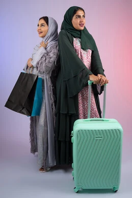 الاستعداد لرحلة سياحية ،قضاء أوقات ممتعة في التسوق برفقة الأصدقاء،امراه سعوديه تحمل بيدها اكياس التسوق بايماءات البهجه والسعادة،  بورتريه لسيدتان عربيتان خليجيتان اماراتيان ترتديان الحجاب والعباءة مبتسمتان ، تنظران الى مكان ما بإيماءات السرور ، مفهوم الأنوثة والنعومة، الاهتمام بالأناقة والمظهر الخارجي،  خلفية ملونه