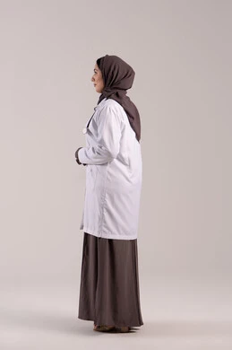 Providing medical assistance to patients, professions and jobs for women, a young Saudi woman working in clinics and hospitals, a side portrait of an Emirati Gulf Arab female doctor wearing a white medical coat and a stethoscope, the concept of medicine and healthcare, full-body, brown background.
