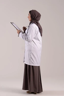 Note-taking and data recording, working in centers and hospitals, medicine and healthcare, a side portrait of an Emirati Gulf Arab female doctor wearing a white medical coat, holding a stethoscope and a clipboard in her hand, a young Saudi woman providing medical assistance, full-body shot, brown background.