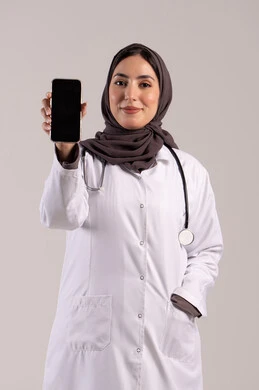 عرض التطبيقات والبرامج الصحية، بورتريه لطبيبة عربيه خليجيه اماراتية ترتدي المعطف الأبيض و السماعة تحمل بيدها الهاتف المحمول تنظر إلى الكاميرا، استخدام الأجهزة التقنية الحديثة ودمج التكنولوجيا مع الطب، عرض شاشة سوادء فارغة، خلفية بنية