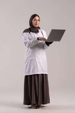 A young Saudi woman provides therapeutic services in medical centers and hospitals, recording and documenting patient information and files via a laptop, integrating modern technology in the field of medical work, a portrait of an Arab Gulf Emirati doctor wearing a white medical coat and a stethoscope holding a laptop, full-body, brown background.