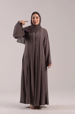 Hand signals and movements indicating this place (here), pinpointing a specific object, a portrait of a veiled Emirati Gulf Arab woman wearing an abaya pointing with her index finger to her face, an elegant young Saudi woman, full-body image, brown background.