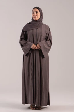 Full-length body, an elegant young Saudi woman, gestures of joy and happiness, attention to appearance, the concept of femininity and elegance, a portrait of a smiling Emirati Gulf Arab woman wearing an abaya looking at something, brown background.