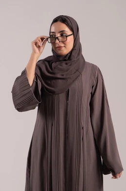 الاهتمام بالمظهر الخارجي، بورتريه لامرأة عربية خليجية اماراتية محجبة ترتدي عباءة تمسك بيدها نظارة طبية، ارتداء النظارات الخاصة بضعف النظر، تحسين الرؤية ومحاولة تعديل البصر، شابة سعودية انيقة، خلفية بنية