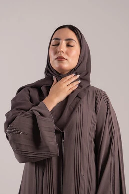 الشعور بالمرض والكحة، تعابير الالم والارهاق، الانفلونزا والتهاب الرئة، بورتريه لامرأة عربية خليجية اماراتية محجبة ترتدي عباءة تضع يدها حنجرتها بايماءات التوجع، شابة سعودية مريضة، خلفية بنية