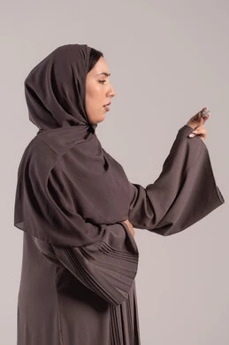 اتباع إجراءات السلامة والوقاية، الإحساس بالمرض والإرهاق، الحاجة لزيارة الطبيب ووضع خطة علاجية، الإصابة بالحمى والتعب، بورتريه  من الجانب لامرأة عربية خليجية اماراتية محجبة ترتدي عباءة تحمل بيدها ميزان حرارة رقمي، شابة سعودية مريضة، خلفية بنية