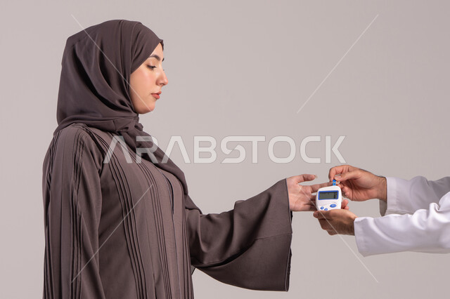 قياس معدل السكر في الدم عبر أجهزة منزلية، بورتريه مقرب ليد ممرض يرتدي اليونيفورم يقوم بفحص نسبة السكر في الدم لمريضة عربية خليجية إماراتية ترتدي العباءة، شركات الرعاية الصحية المنزلية، فحص طبي سريع في البيت، خلفية بنية