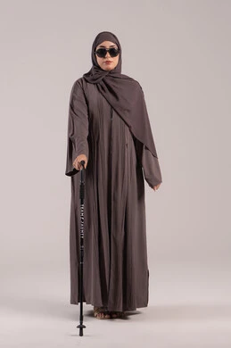 اعتماد الضرير على العصا في الحركة اليومية, مفهوم الصحة والمرض, فقدان الرؤية والبصر, بورتريه من الجانب لامرأة عربية خليجية اماراتية كفيفه مصابة بالعمى ترتدي النظارة الشمسية و بيدها العكاز، الجسم بالطول الكامل, خلفية بنية