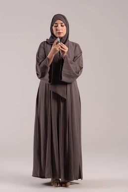 Respiratory problems, a sick young Saudi woman, maintaining an open airway, a portrait of a veiled Emirati Gulf Arab woman wearing an abaya holding an asthma inhaler in her hand, inhaling cough medication, full-body image, brown background.