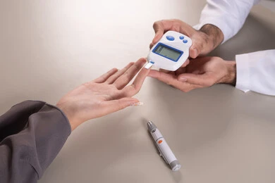 Checking blood sugar levels using portable devices, a close-up portrait of a nurse's hand wearing a uniform checking the blood sugar level of an Emirati Gulf Arab patient wearing an abaya, home nursing companies, medical care and rapid testing, brown background.